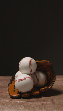 Vídeo-Vertical-De-Primer-Plano-De-La-Naturaleza-Muerta-De-Béisbol-Del-Estudio-Con-Pelotas-Y-Guantes-De-Receptor-En-El-Suelo-De-Madera-2